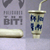 Pixelated image showing a blue and white ceramic cup with a straw on the right, next to abstract gray shapes and a horizontal bar on a light purple background.