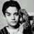 Black-and-white pixelated image of a person with short dark hair wearing a dark jacket over a light shirt, positioned against a plain light background.