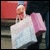 A person holds two shopping bags against a blurred background, with pink and white text reading 'a girls dream' on adjacent