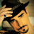 Pixelated static image of a person with dark hair and light skin making a hand gesture near their face against a blurred background.