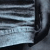 A static pixelated image showing a partial view of horizontal light blue and dark gray stripes with a curved black edge on the right side.
