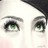 A close-up of a stylized cartoon face with large green eyes and black hair, rendered in low-resolution pixel art style on a white background.