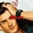 A person with dark hair and a black wristband holds their hand to their head, with a red heart symbol above and red text reading "Meet" on the left side.