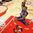 A basketball player in a blue jersey jumps toward the hoop on a court with red and white markings, captured across showing motion
