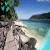 Pixelated beach scene with rocky shore, turquoise water, distant landmass under blue sky.