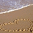 Beach scene with sand drawing of a heart and text reading "I think of" on left, transitioning to "I only draw" on right.
