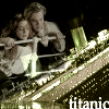 Static image of two people embracing on a ship's railing with a golden ship hull and water background, text 'titanic' visible at bottom right.