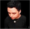 A person with short dark hair wearing a black shirt and silver necklace appears in showing text animation
