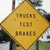 Yellow diamond-shaped sign with three lines of pixelated text reading '10005', '1131', and '80015' against a blurred background of trees and a building.