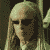A pixelated animated sequence shows a figure with long light hair and dark sunglasses, shifting from a forward-facing pose to a side profile while maintaining a neutral expression.