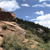 Pixelated landscape showing rocky terrain under a blue sky with scattered clouds, rendered in low-resolution style with visible pixelation.
