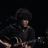 Four distinct images arranged in a : top-left shows a person playing guitar, top-right is a close-up of curly hair, bottom-left features three people in formal suits, and the bottom-right is empty