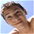A 50x50 pixel animated contact sheet showing two frames of a buddy icon with a person on the left and green text logo on the right against a blue sky background.