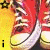 Red high-top sneakers with white laces and soles on a yellow background, featuring pixelated text elements.