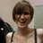 A pixelated static image shows a person with short brown hair and dark sunglasses, wearing a light-colored sleeveless top against a muted background.