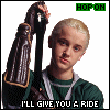 A person with short blonde hair holds a dark object with a brown strap, wearing a green sweater over a white shirt, with text above and below.