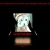 Pixelated image of a ghost-like figure with two dark eyes and mouth on a light body, standing atop stacked brown rectangular shapes against black background.