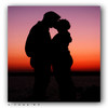 Silhouette of two figures embracing against a gradient sunset sky with purple to orange hues.
