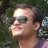 Pixelated close-up of a person's head and shoulders against dark green foliage background, wearing sunglasses with light-colored frame.