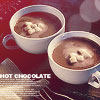 Two white ceramic mugs filled with brown liquid topped with white cream, placed on a dark surface with a red background.