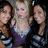 Three people pose together in a pixelated image with a dark background, wearing casual clothing in muted tones.