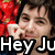 Pixelated image of a person holding a red object with white text, overlaid by large bold text reading "Hey Ju".