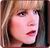 Pixelated close-up of a person with light brown hair, fair skin, and red lips, set against a blurred background with warm tones.