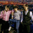 Pixelated image of three people walking outdoors with pink text overlay about love and heartbreak on black background.