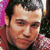 Pixelated static image of a male celebrity's face with dark hair and light skin, set against a blurred background with pink and purple tones.
