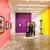 Pixelated image showing a purple door with a white square, a figure in dark clothing, and pink and yellow background sections.