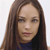 A static pixelated image of a person with long brown hair wearing a dark blue top against a light background.