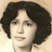 Pixelated portrait of a person with dark curly hair against light background, static image.