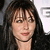 A pixelated close-up of a person with dark hair and bangs, wearing a dark top against a light background with partial text.