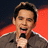 A pixelated image shows a person holding a microphone against a red and dark background with text reading DAVID ARCHULETA in red letters.