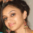 Pixelated close-up of a person with dark hair, light skin tone, and visible ear; background is blurred neutral tones.