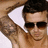 A pixelated static image shows a person with dark hair wearing sunglasses and a white triangular headpiece against a brown background.