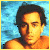 Pixelated portrait of a person with dark hair against a blue gradient background, wearing an orange top.