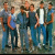 Six pixelated figures in casual clothing stand closely together against a blurred background with muted tones.