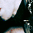 A static image of a person with platinum blonde hair, dark eye makeup, and red lips against a black background.