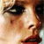 A pixelated close-up of a person's face showing eyes, nose, and mouth with dark hair and red lips against a light background.