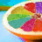 A sliced citrus fruit with multicolored segments in red, purple, green, and orange against a blue background.