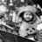 Pixelated grayscale image of a cartoon character with large eyes, wide smile, and rounded head against dark background.