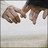 Two hands clasped in a handshake gesture, with one hand slightly raised above the other against a light background.