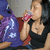 A woman in a black tank top drinks from a pink cup while seated next to someone in a purple hoodie, with the right side of the image cropped.