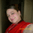 Pixelated image of a person with light skin wearing red clothing, positioned against a dark background with vertical elements.