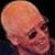 Pixelated close-up of a bald human head with smooth skin tones and dark eye sockets against a black background.
