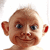 Pixelated close-up of a bald humanoid figure with large ears, dark eyes, and a slight smile against white background.