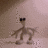 Pixelated figure with dark rectangular head covering, brown limbs and torso against light pinkish-brown background.