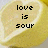 A lemon slice with pixelated text 'love is sour' overlaid, displayed in a