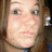 Pixelated close-up of a person's face with light skin, brown hair, and neutral expression against blurred background.